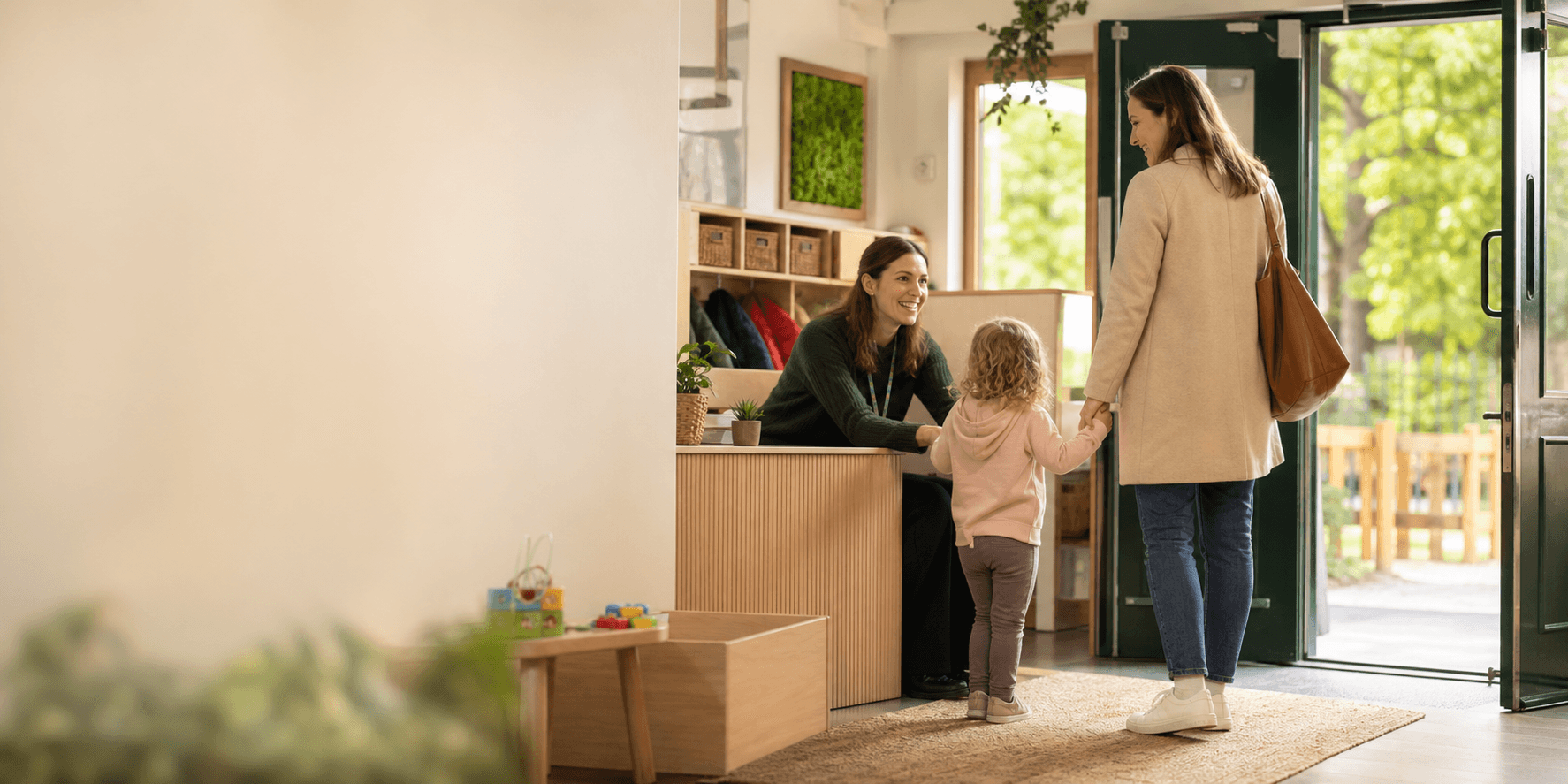 A nursery practitioner welcoming a parent and child at reception
